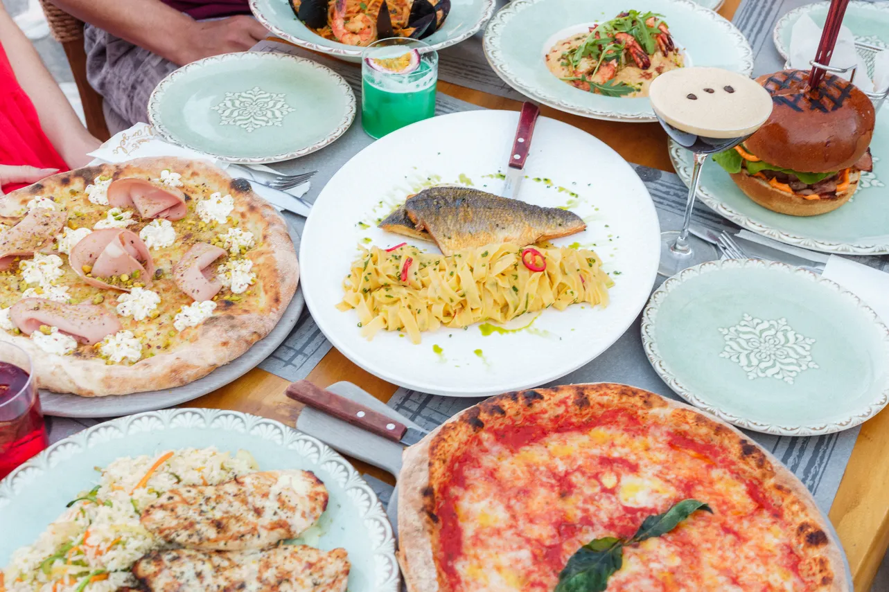 Table spread of pizza, grilled fish, and burger at d'angelo